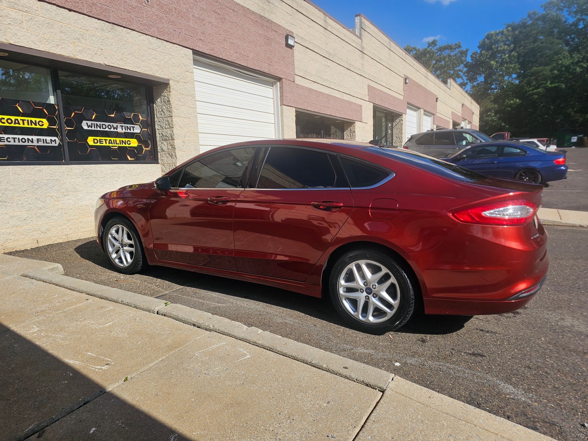 Red car parked in front of a building with a closed garage door.