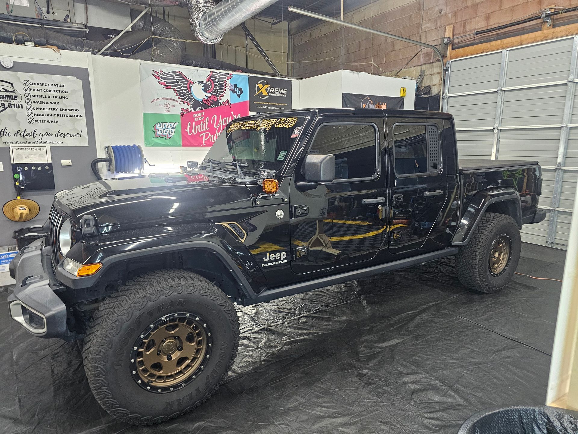 Black Jeep Gladiator pickup truck inside a garage.