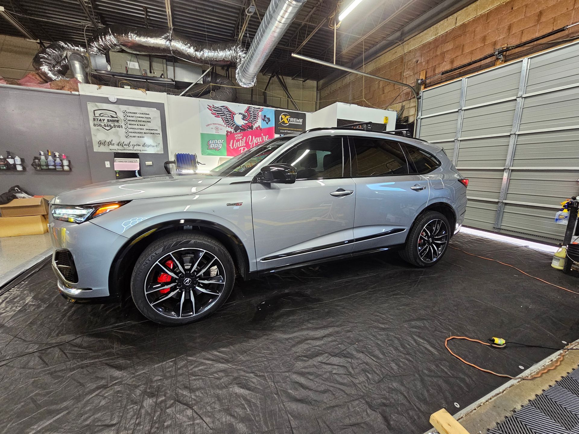 Silver Acura SUV parked in a garage with black rims and red brake calipers.