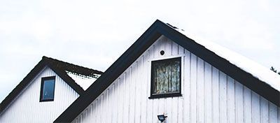 White house gables with black trim and windows against a bright sky