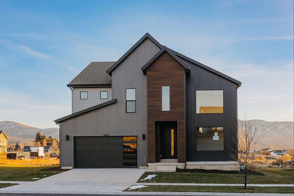 Modern two-story gray house with dark roof and garage in a suburban neighborhood
