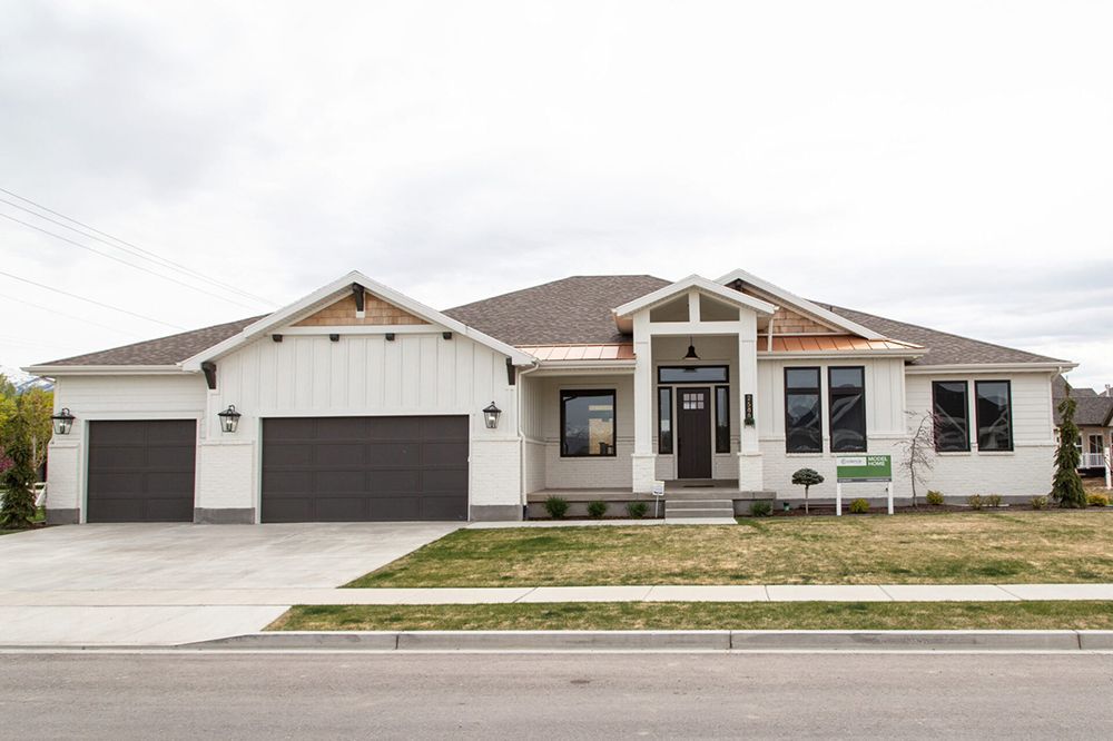 Single-story suburban house with three-car garage, white exterior, and front lawn.