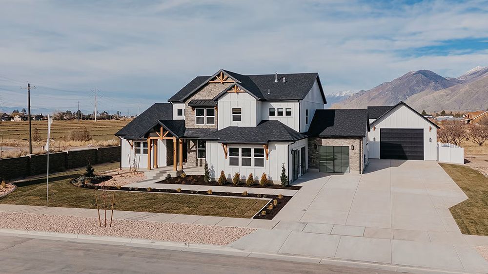 Modern two-story suburban house with a driveway, garage, and mountains in the background