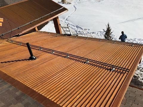 Copper-colored ribbed roof with roof-mounted solar panels on a snowy mountainside