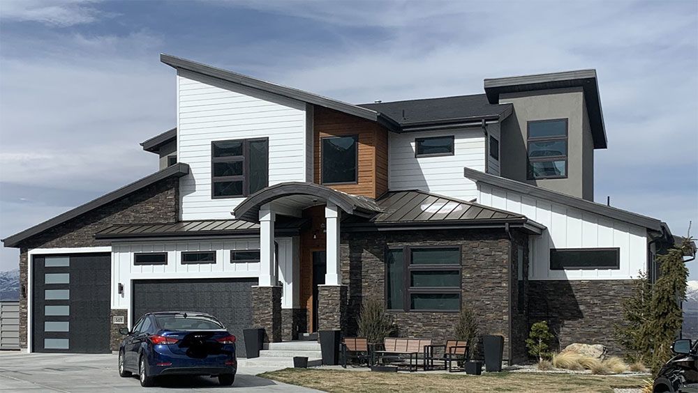 Modern two-story house with white and gray siding, black accents, and a blue car parked in the driveway