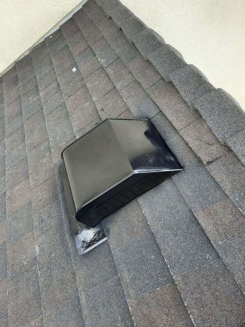 Black vent cap on gray shingled roof