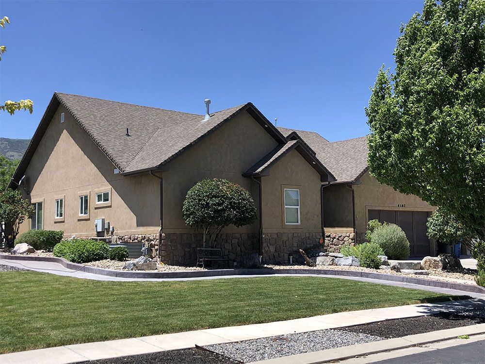 Suburban house with tan stucco, manicured lawn, and blue sky