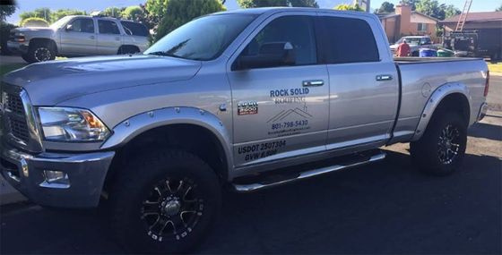 Silver lifted pickup truck parked outdoors, side view with black wheels and chrome accents