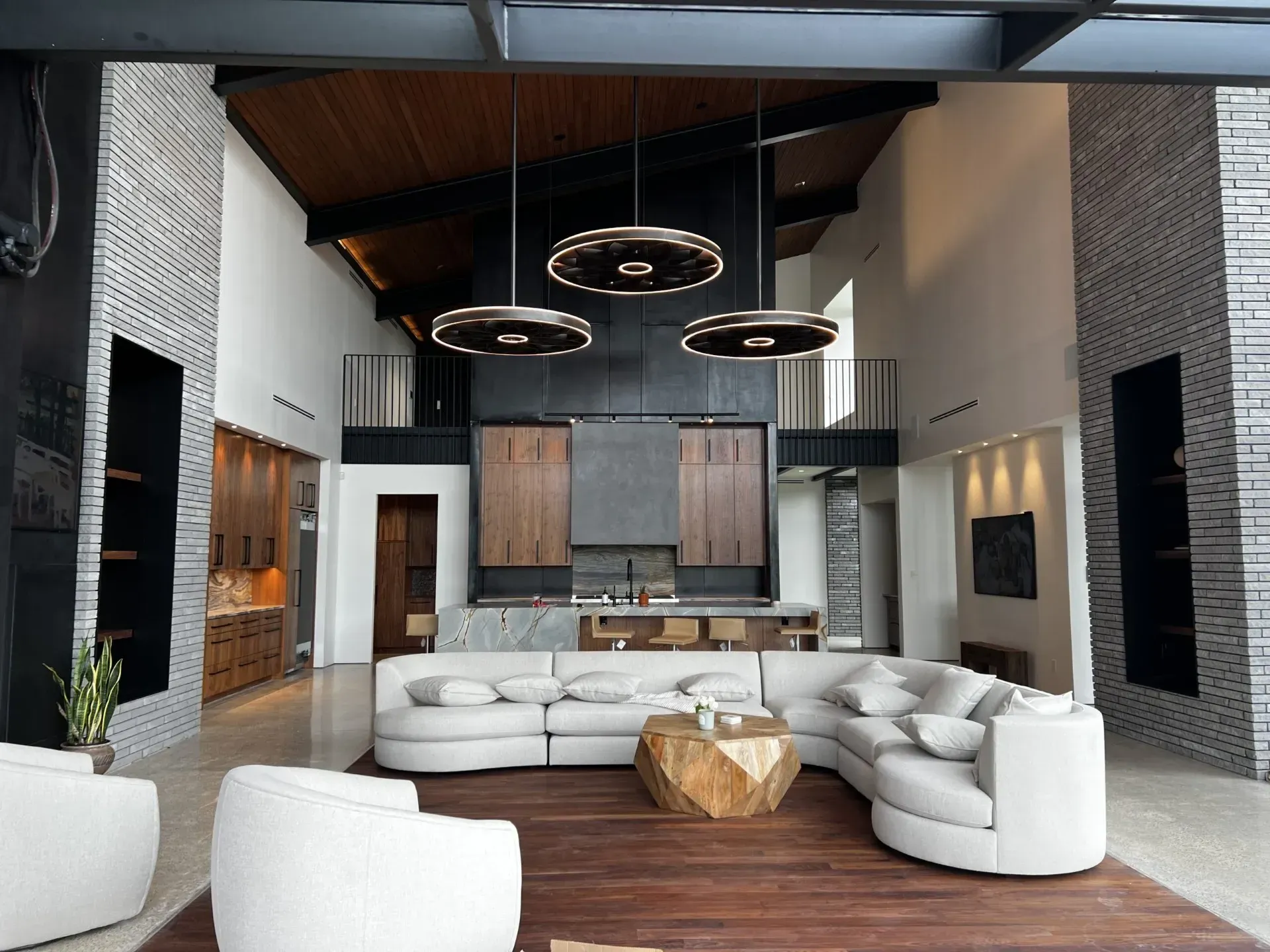 Modern living room with high ceilings, sectional sofa, and pendant lights.