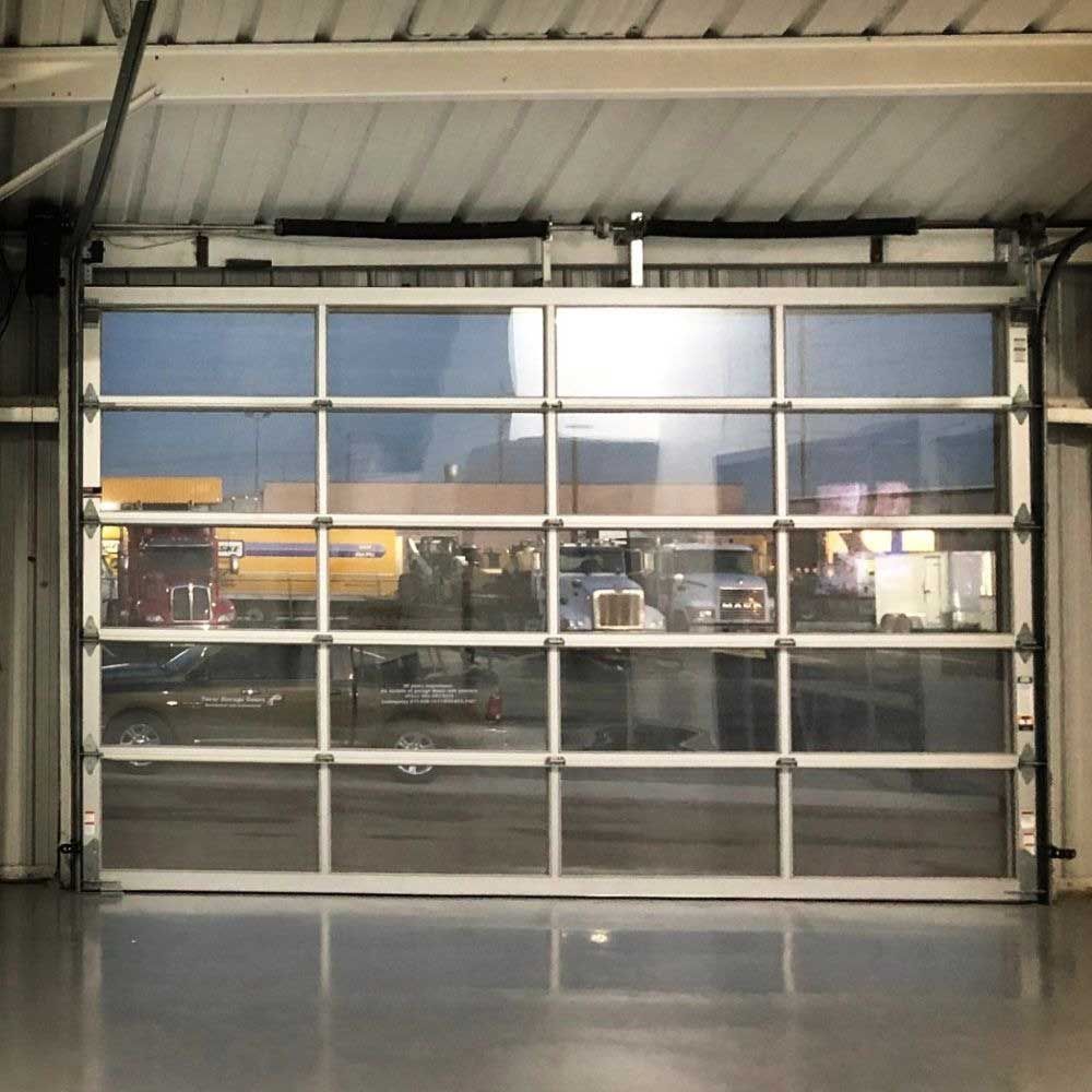 Glass garage door reflecting vehicles parked in front of a building.