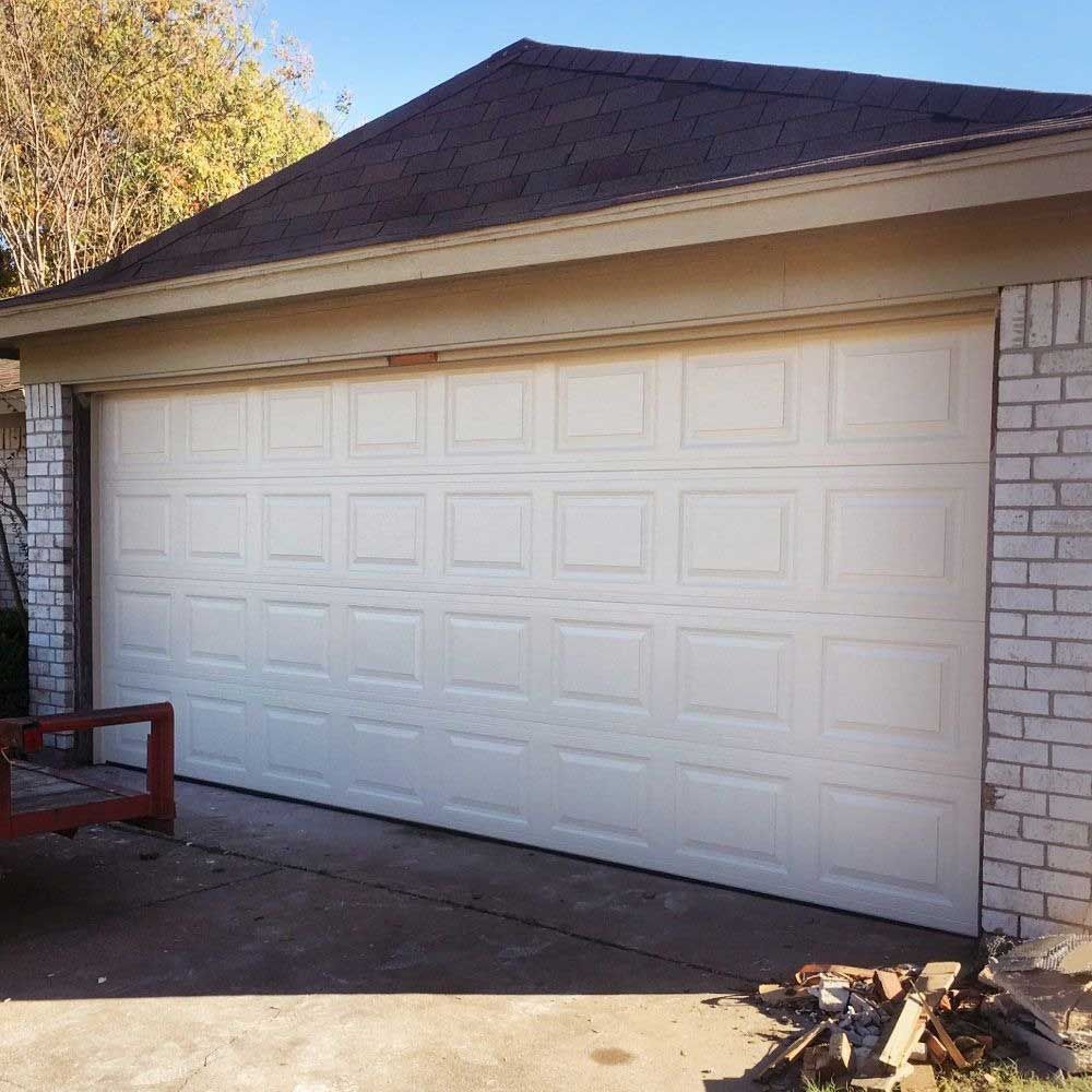White garage door with brick and beige trim. Sunny outdoor setting.