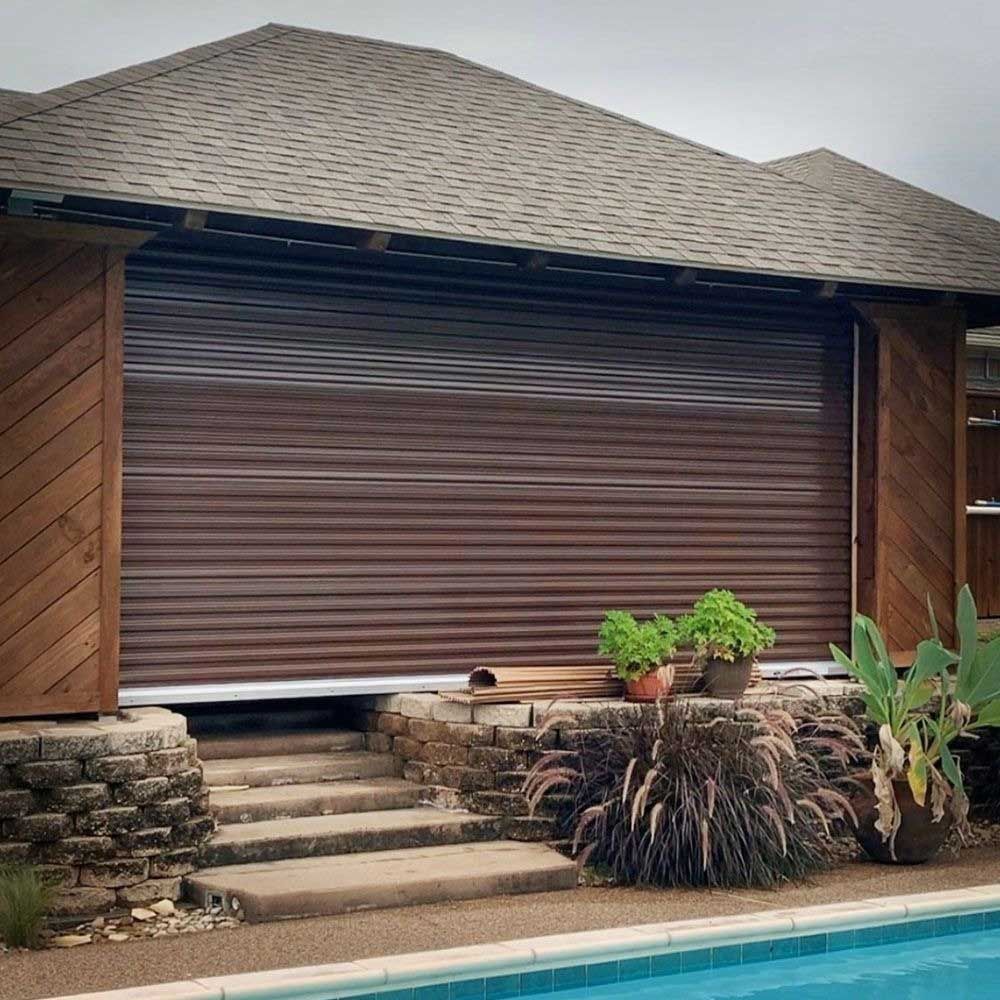Brown roll-down shutter on a building with a stone base, steps, and a pool.