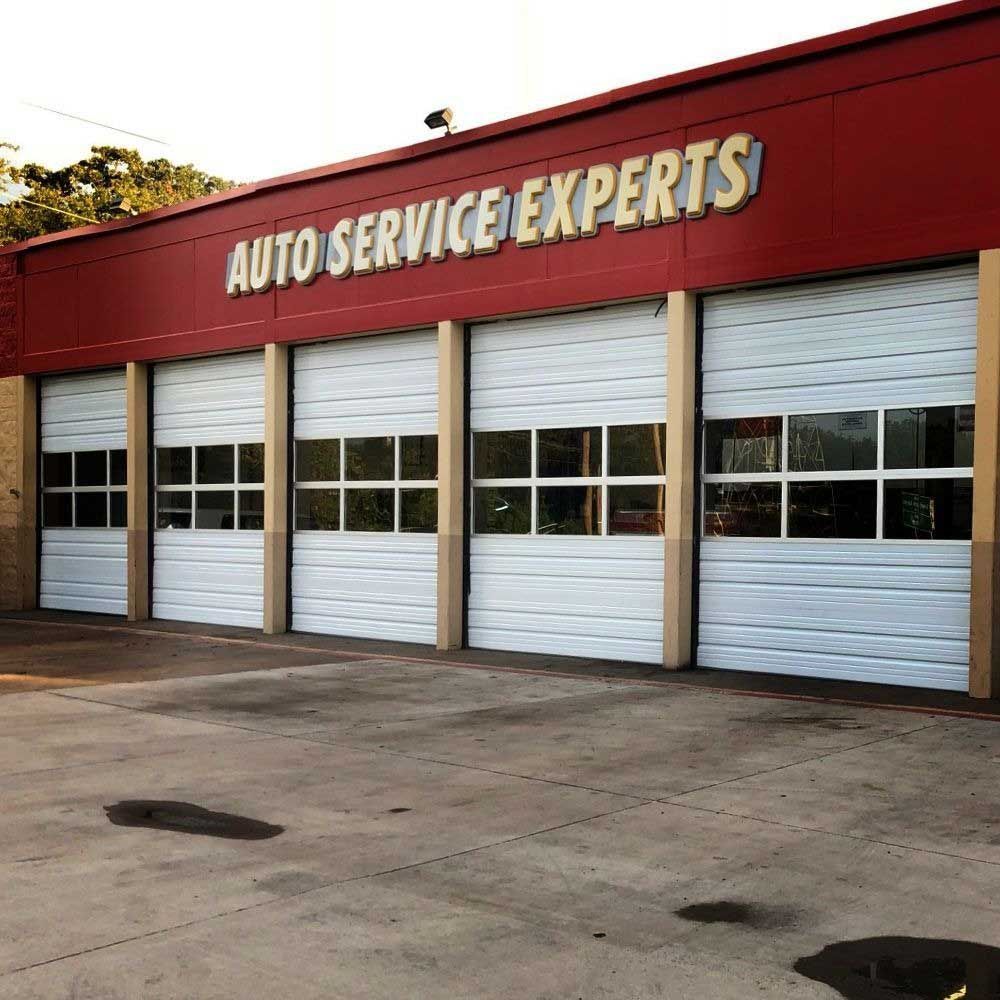 Auto service shop with white garage doors, red trim, and 