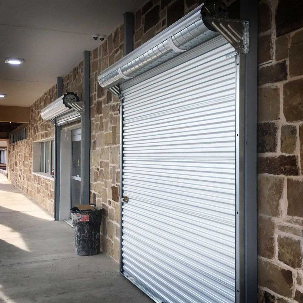 Closed, corrugated metal security shutters on a brick building exterior.