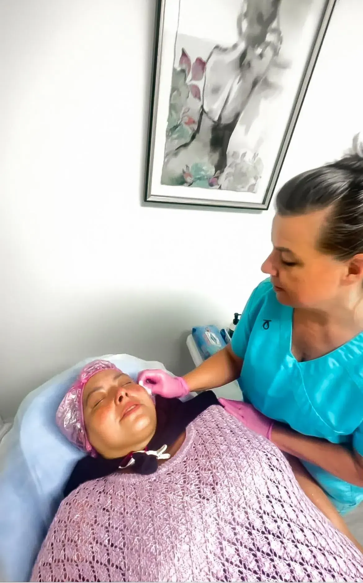 Woman receiving a facial treatment from a healthcare professional in a medical setting.
