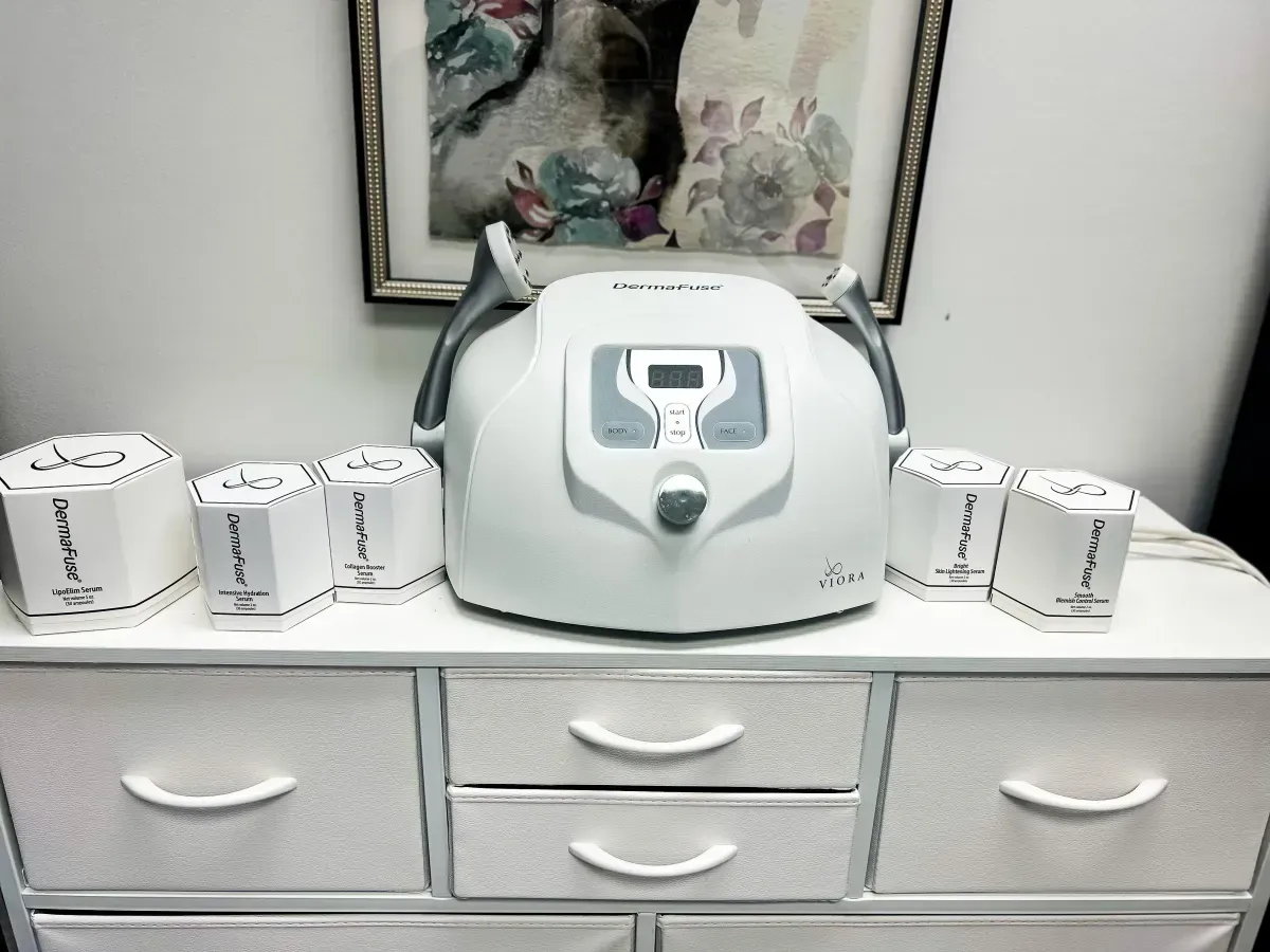 A white medical device with multiple white attachments on a white dresser, under a framed picture.