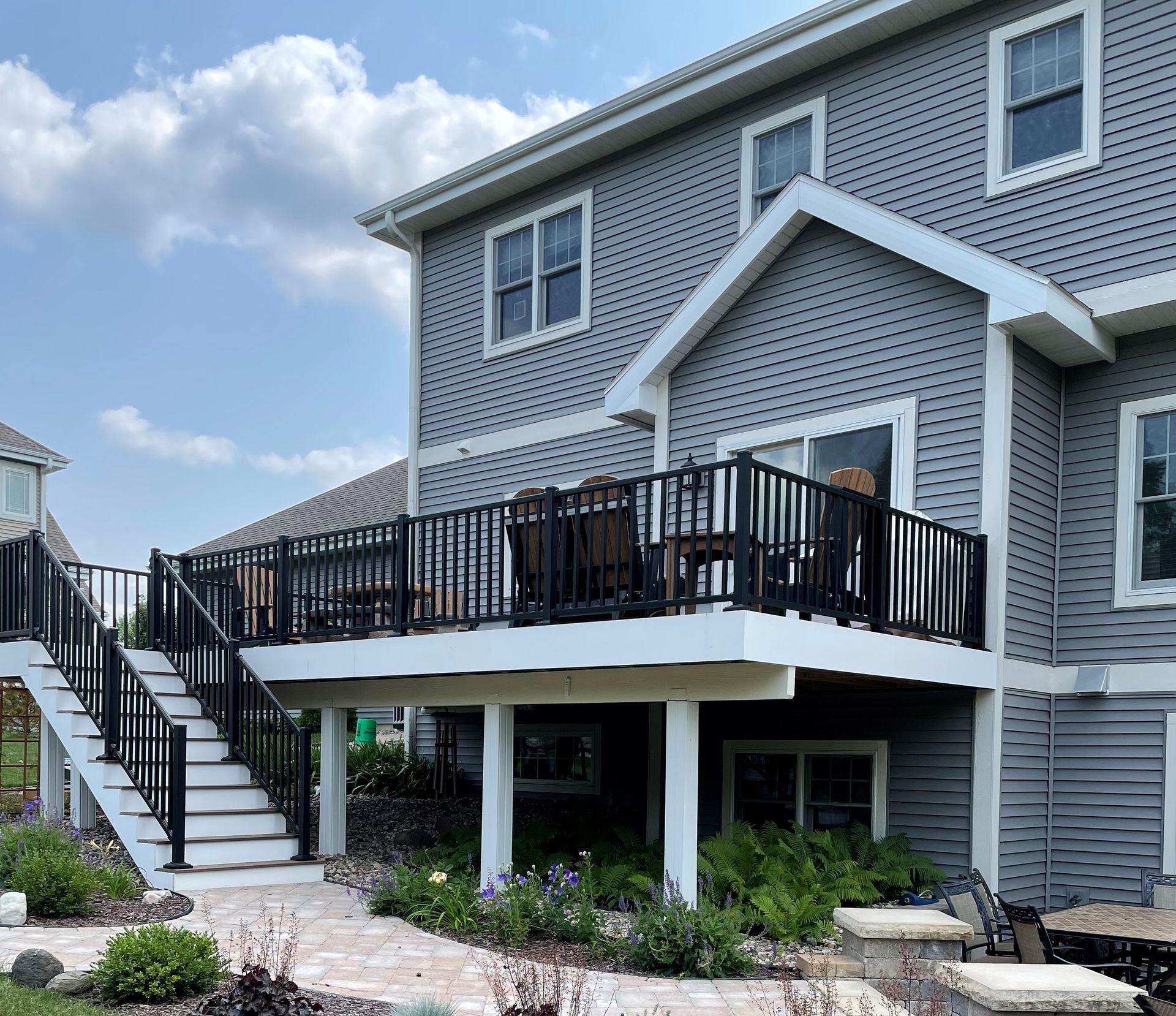 Two-story house with gray siding, white trim, and a black railing deck.