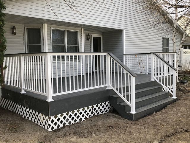 Gray deck with white railings, lattice skirt, and steps leading to a house with siding.