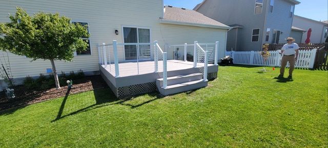 A backyard with a deck and a person standing on the grass.