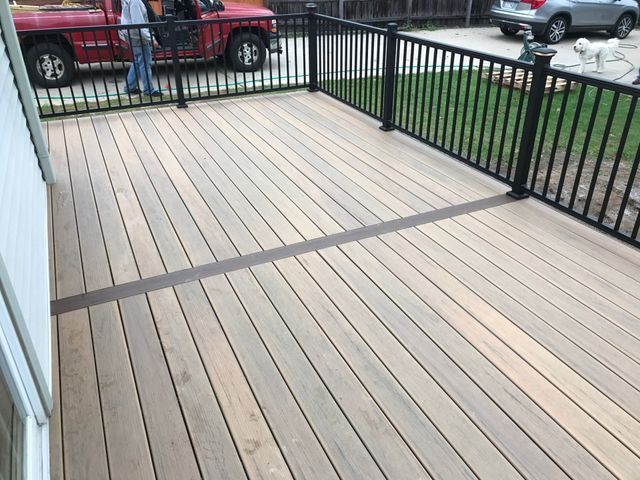 A newly built deck with black railings and light-colored wooden planks.