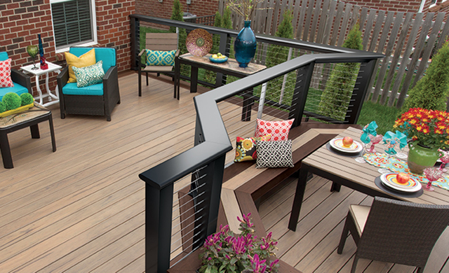 Outdoor deck with seating, decorative pillows, and dining area. Black railings with cable infill.