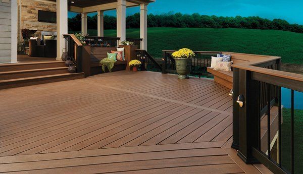 Wooden deck with black railings and composite boards overlooking a green lawn.