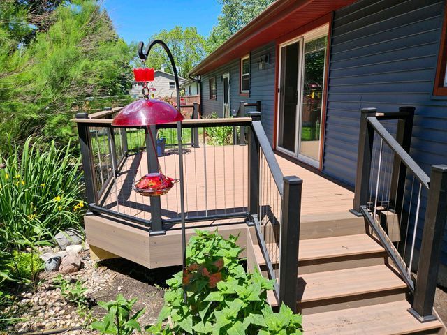 Backyard deck with dark railings, brown composite decking, and a hummingbird feeder.