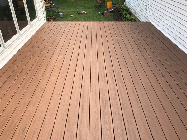 Wooden deck extending from a white house, overlooking a grassy yard.