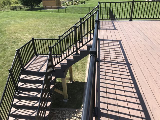 Composite deck with black railing and stairs leading to a grassy yard.