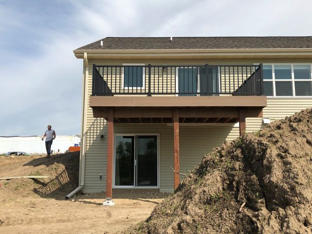 A two-story house with a wooden deck and a person standing nearby.