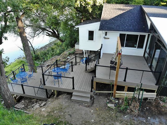 A multi-level deck on a white house overlooking a river. Blue chairs and black railings.