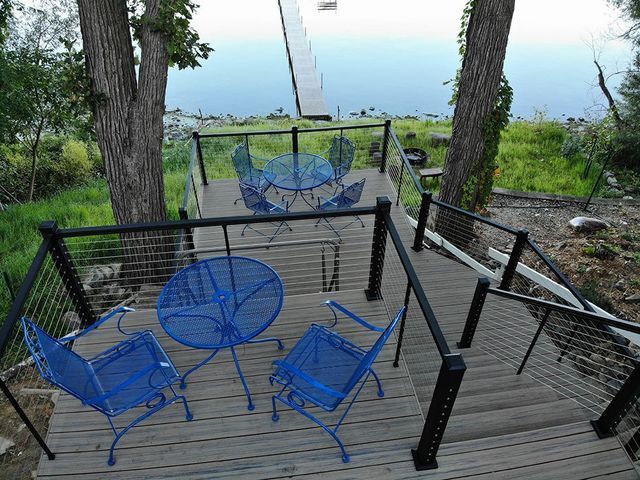 Blue outdoor patio furniture on wooden decks with a view of a lake and dock.