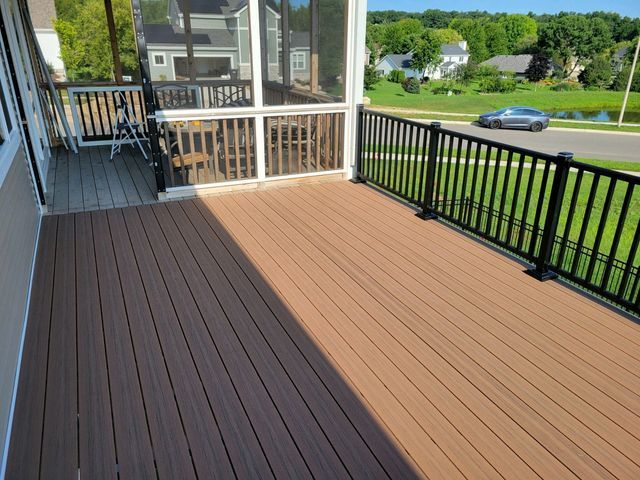 Wood deck with black railing and screened porch overlooking a street and pond.