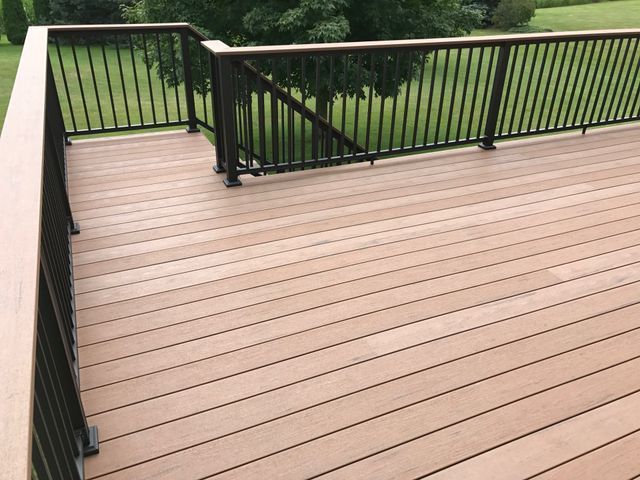 Wooden deck with black railing overlooking a grassy yard.