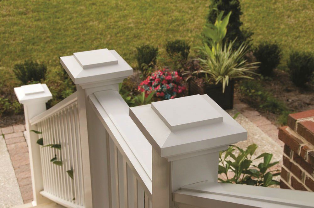 White porch railing with square posts and green lawn in the background.