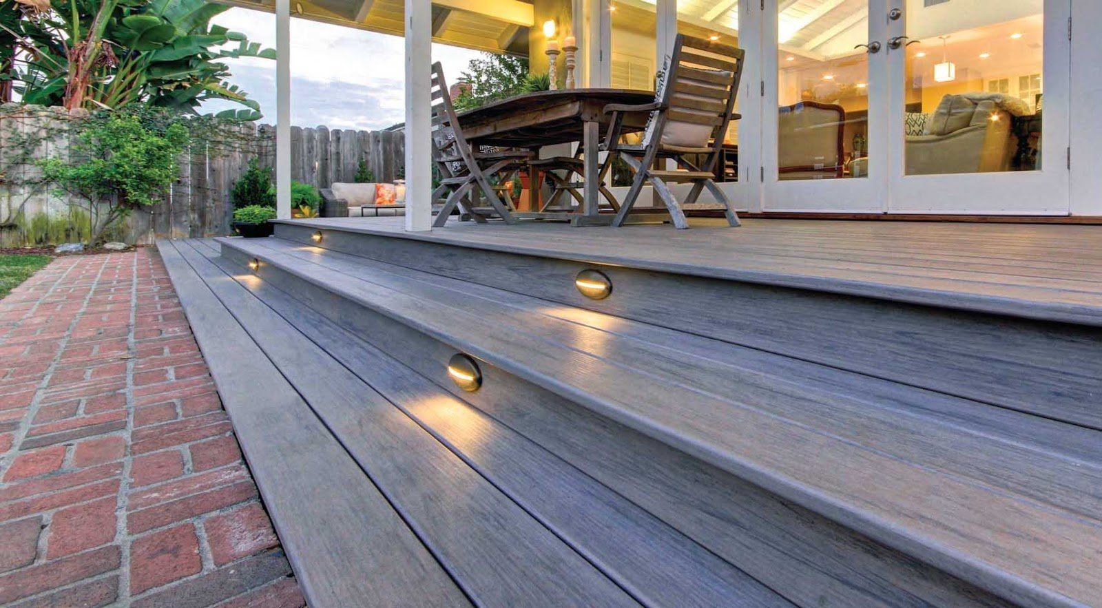 Wooden deck with built-in lights, steps, and a dining table under a covered patio.