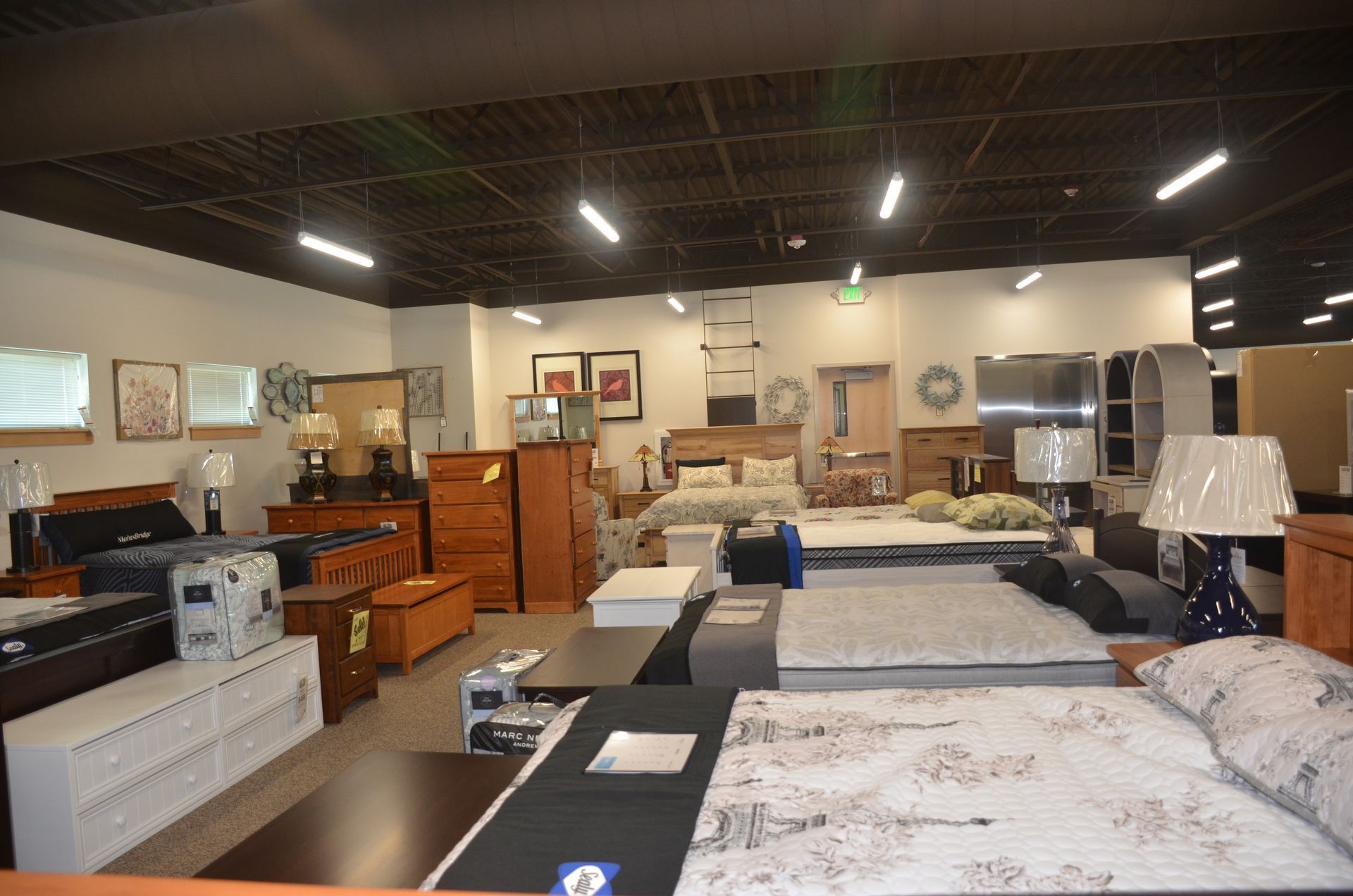 A large room filled with furniture and mattresses in a furniture store.