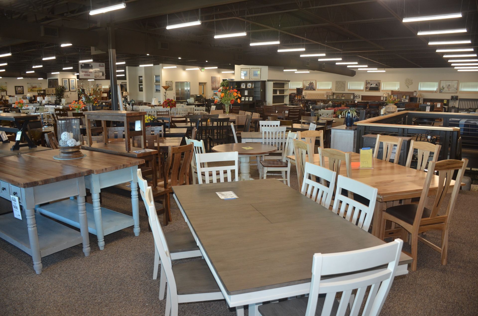 A large room filled with tables and chairs in a furniture store.