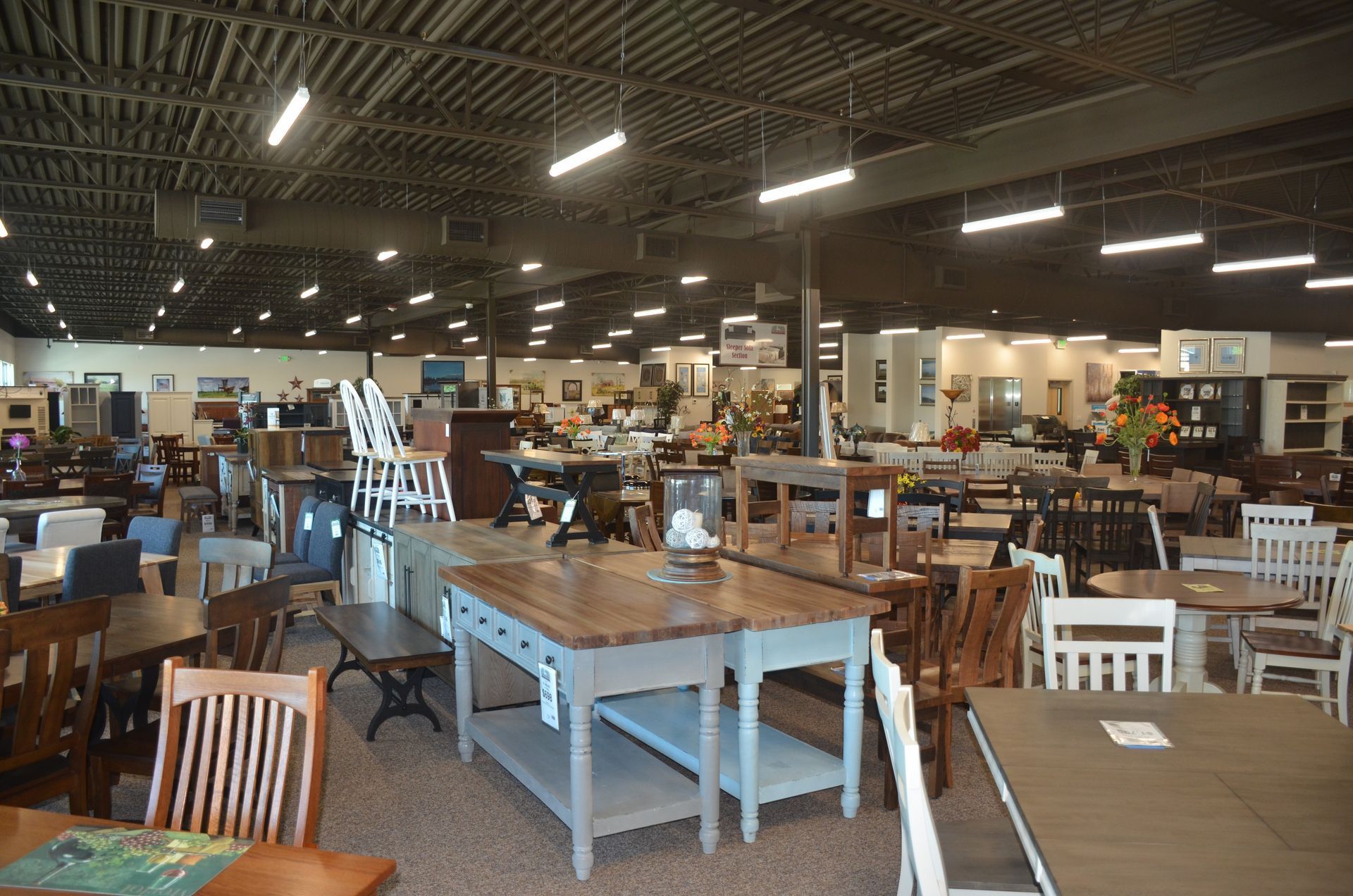 A large room filled with good-looking tables and chairs in a furniture store.
