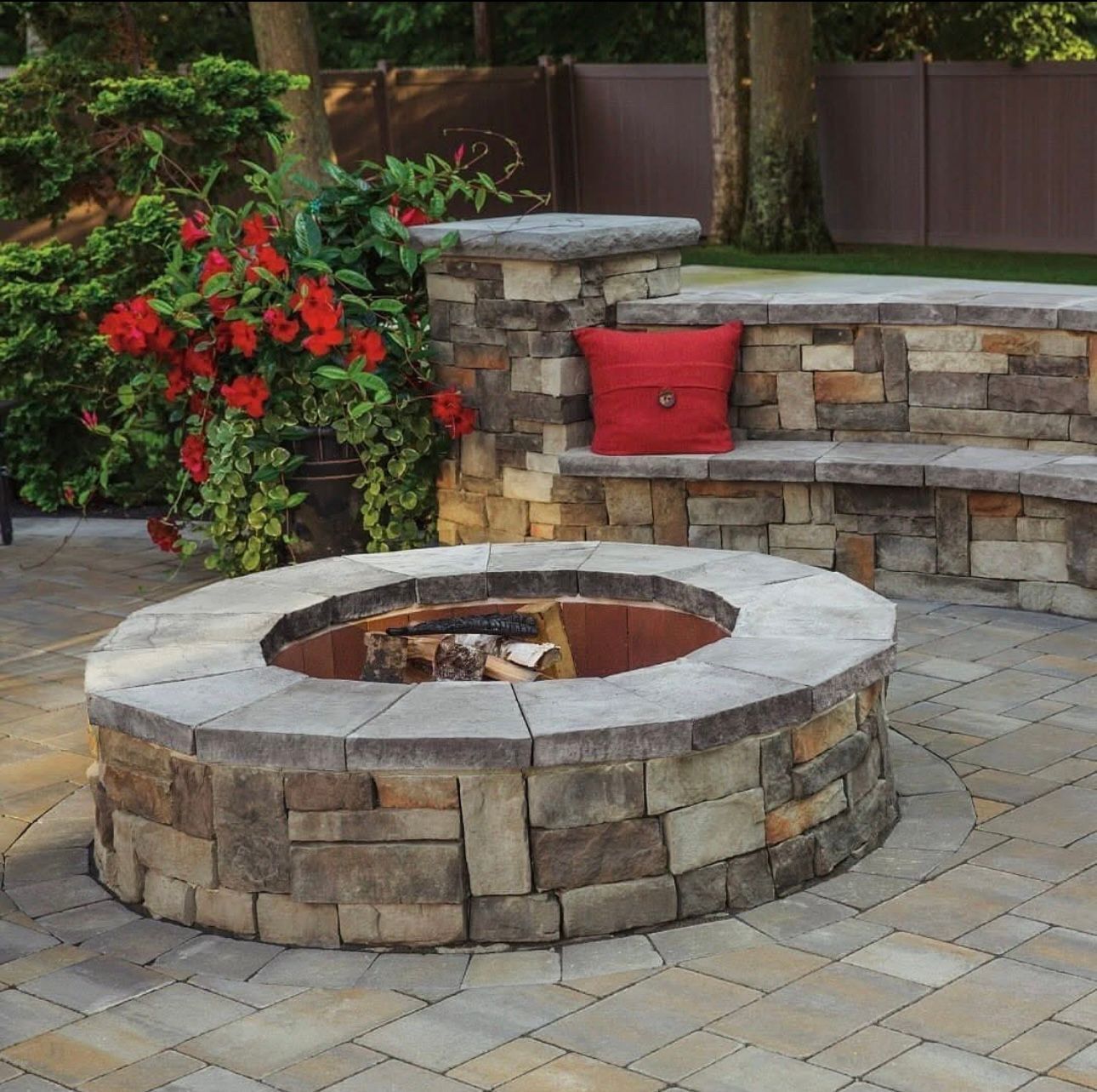 Circular stone fire pit with built-in seating and decorative plants in a landscaped backyard patio.