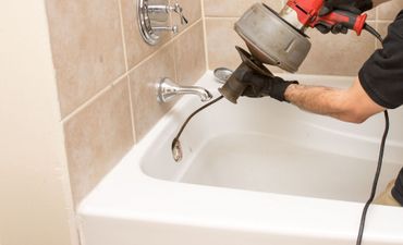 Plumber unclogging a tub drain