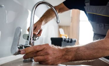 A man is fixing a faucet in a kitchen