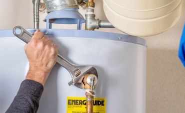 A person is fixing a water heater with a wrench