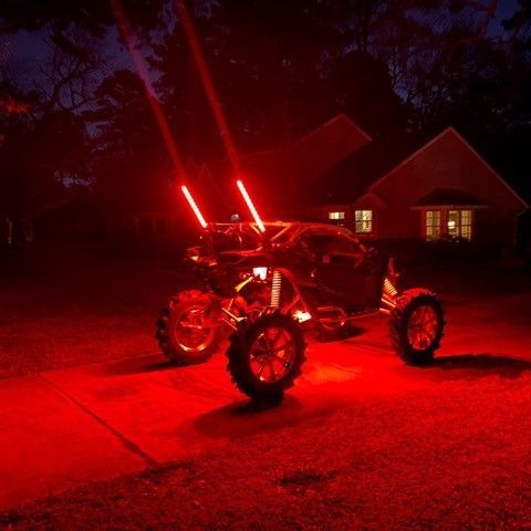 An ATV with red lights is parked in front of a house at night