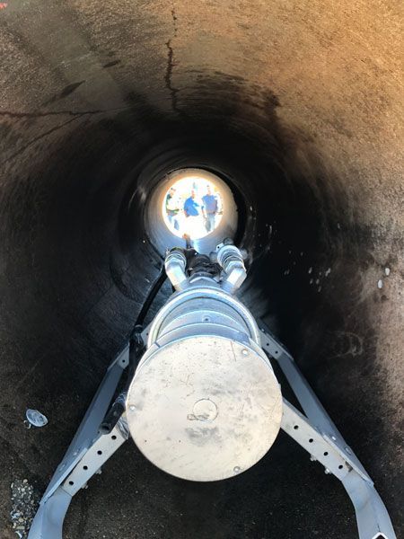 Large pipe interior with a bolted metal pipeline and bright opening at the far end
