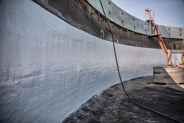 Curved concrete wall coated in fresh white waterproofing on a construction site