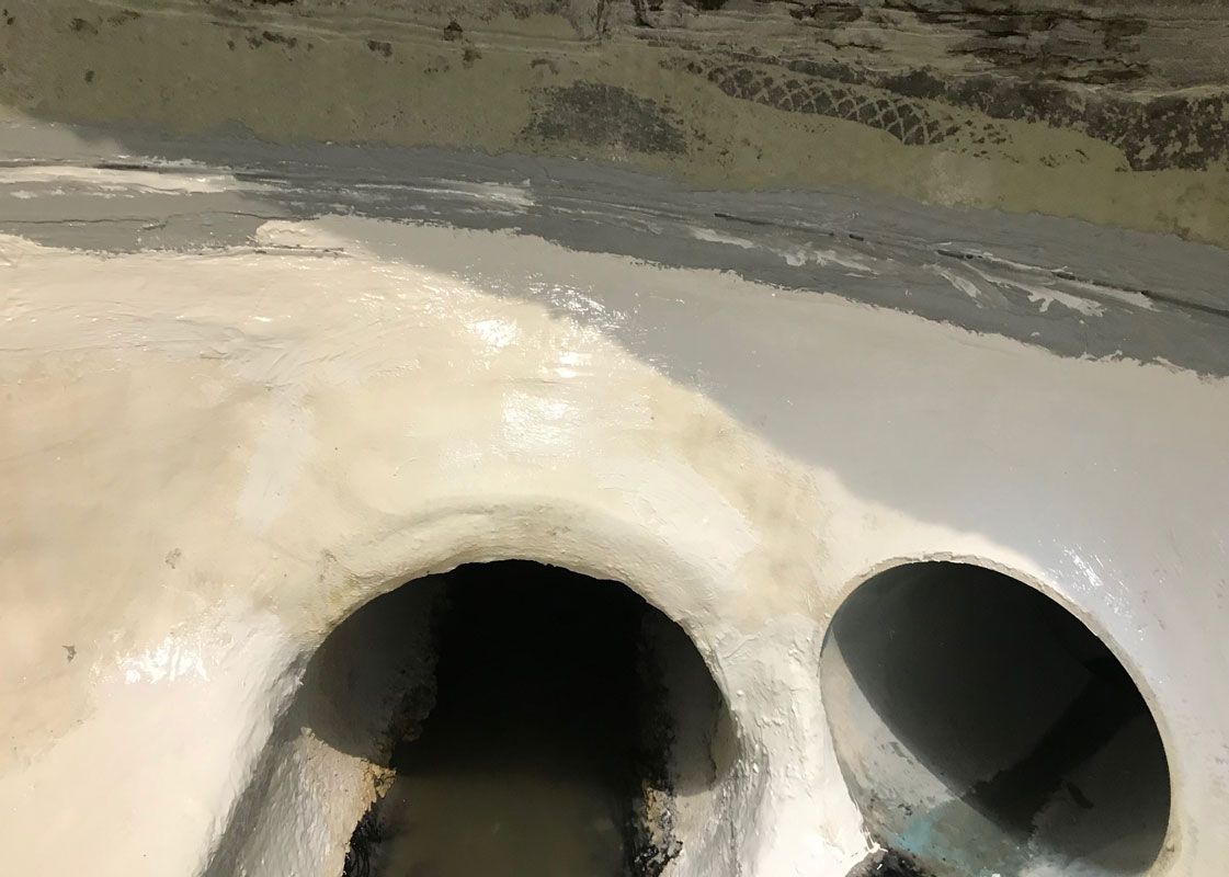 Two circular drain openings in a concrete surface, one dark and one partially visible.