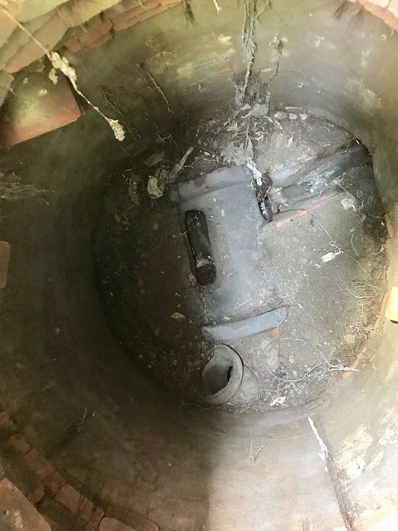 Inside a dark pipe or tunnel, a gray circular metal cap with openings is visible.