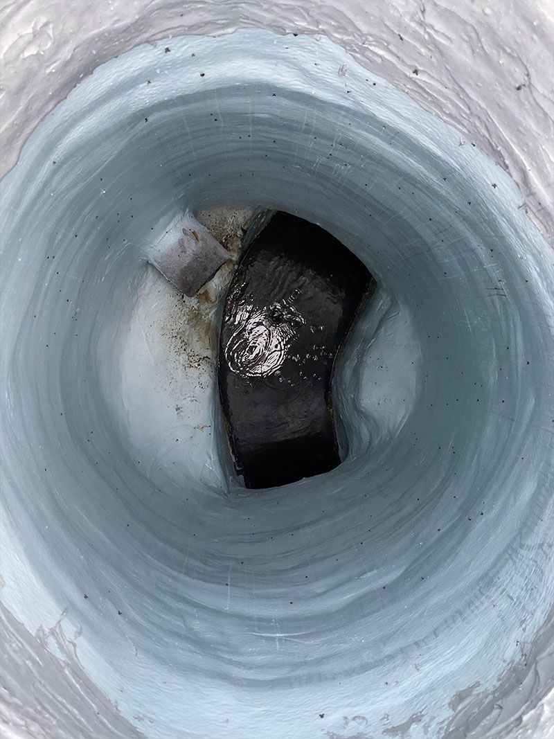 Inside a white cylindrical pipe, a dark opening or blockage is visible near the center.