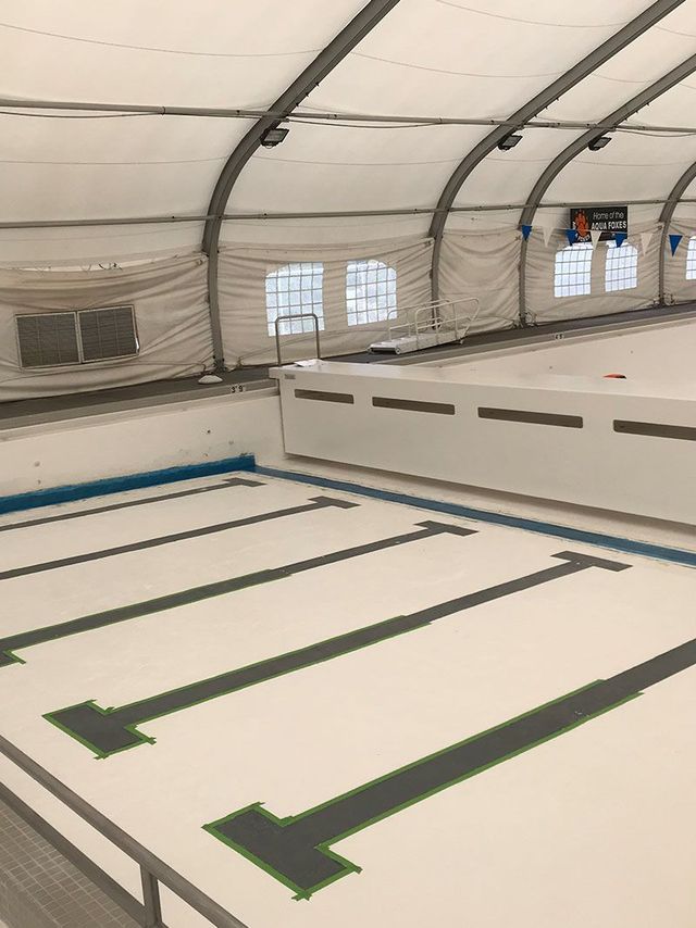 Indoor covered pool with empty lanes marked by black lines and white lane blocks
